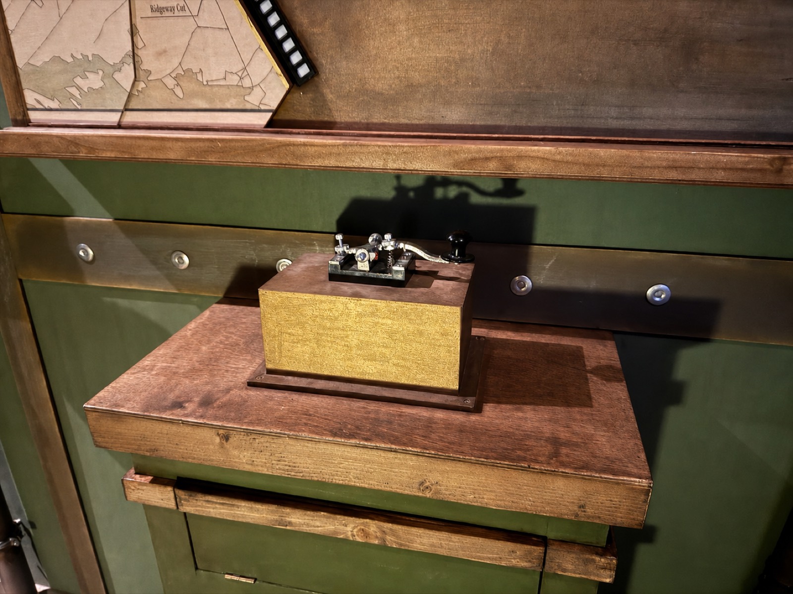 Historischer Telegrafenschlüssel im Waggon, darüber eine Streckenkarte